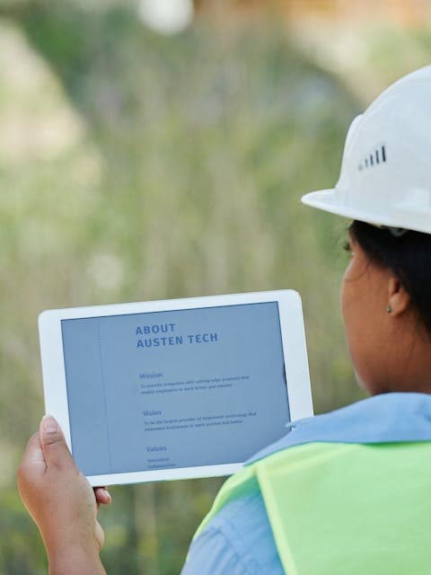 Construction worker in hard hat and hi-vis vest using a tablet on site