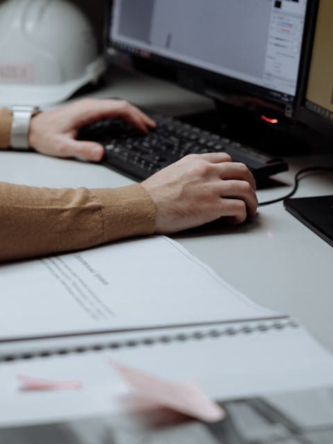 Project manager reviewing drawings and dashboards at an office desk